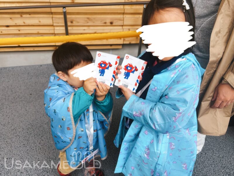 大阪万博2025のスタンプラリーを持って住友館に並ぶ子供達