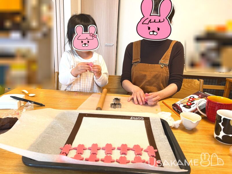 親子でピンク色のクッキー生地を型抜きしている様子
